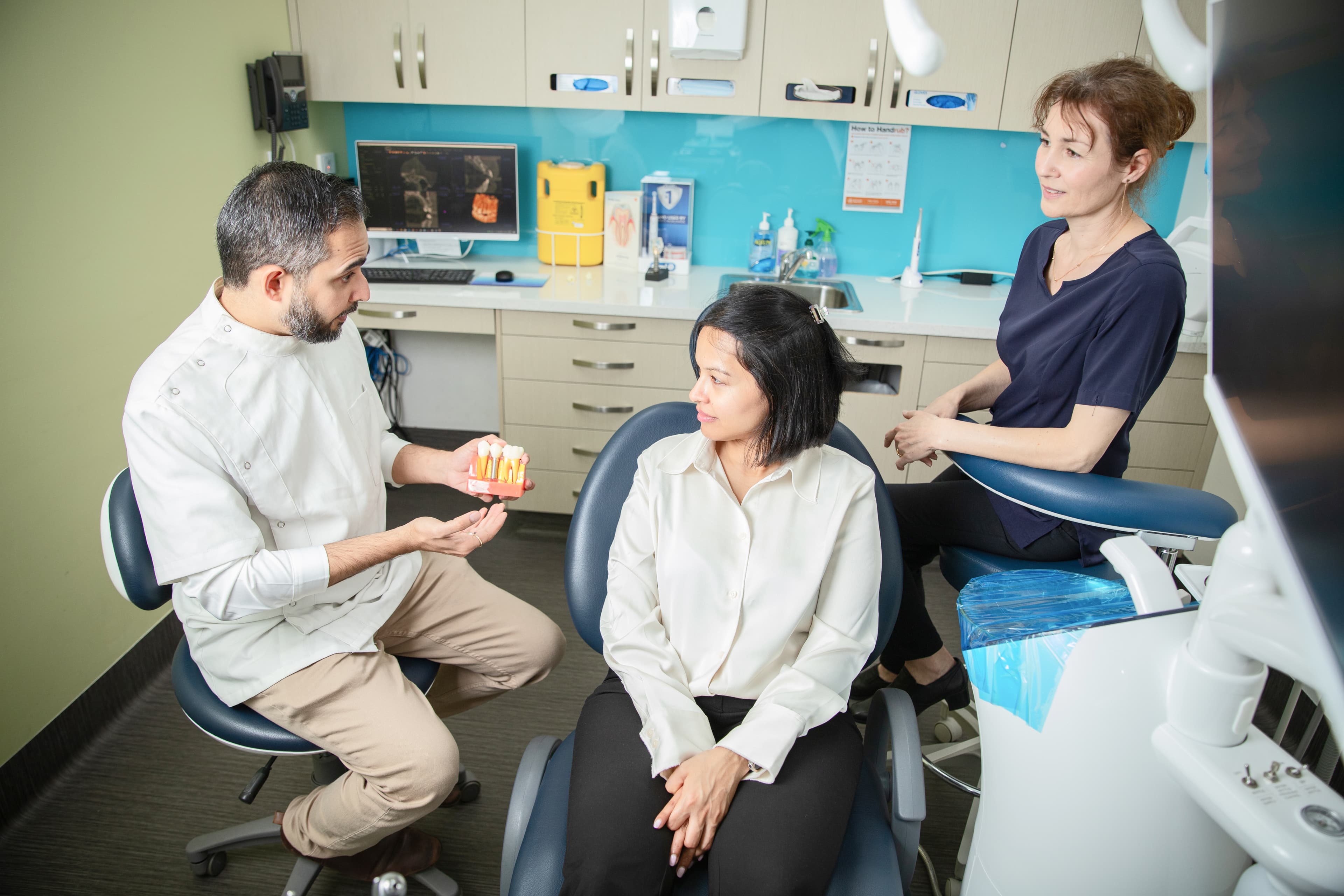A dentist speaking with a person in a treatment room at a dental clinic.