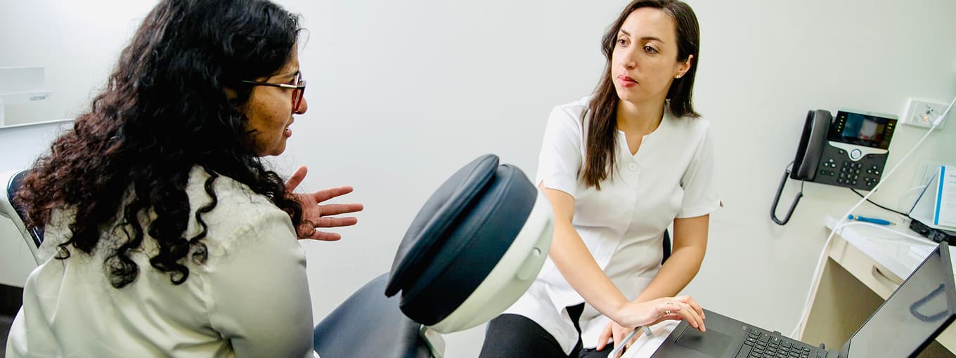 A clinician speaking with a seated person in a consultation room.
