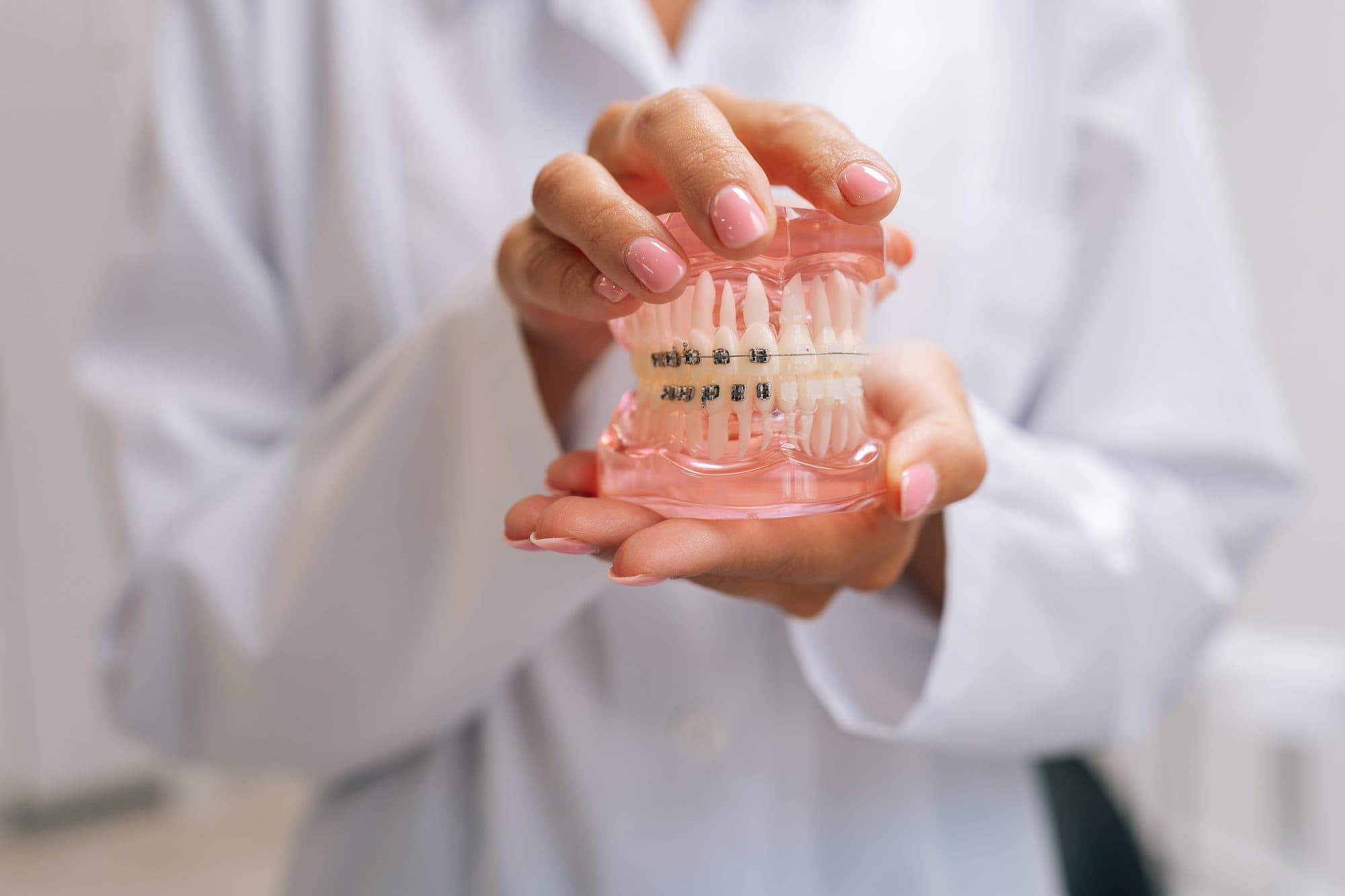 A clinician discussing a clear aligner model with a seated person.