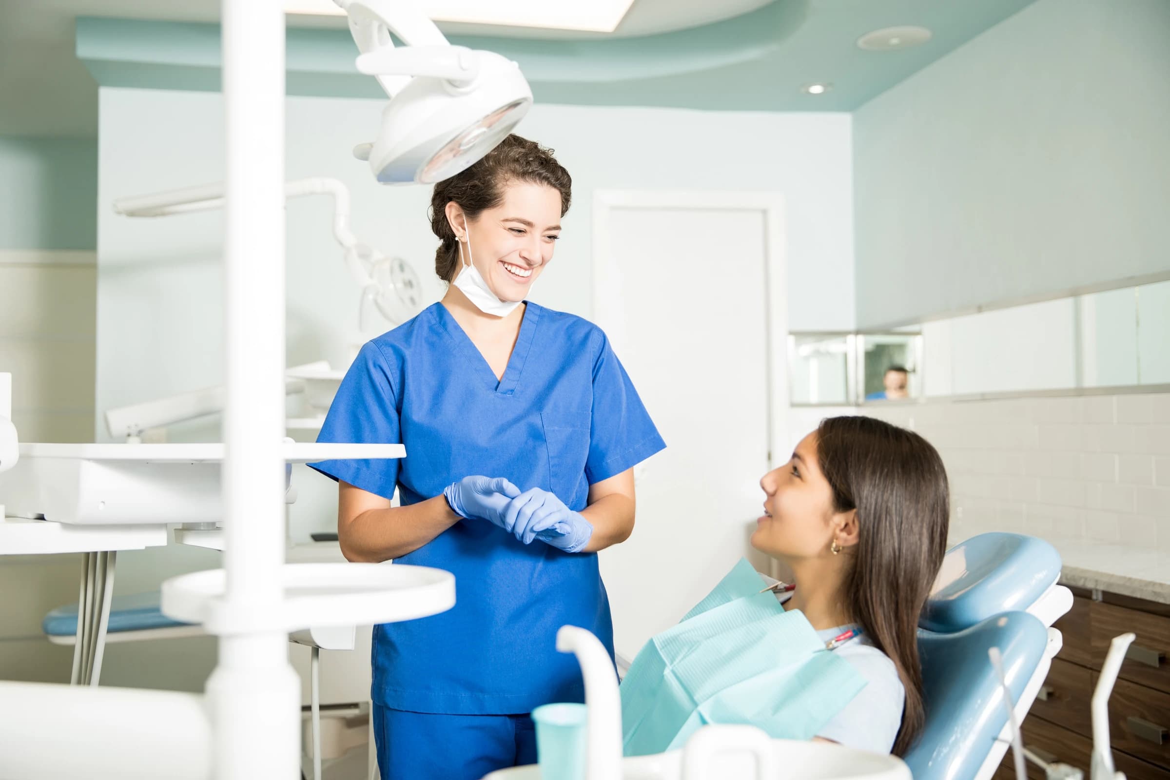 A dentist speaking with a patient seated in a dental chair.
