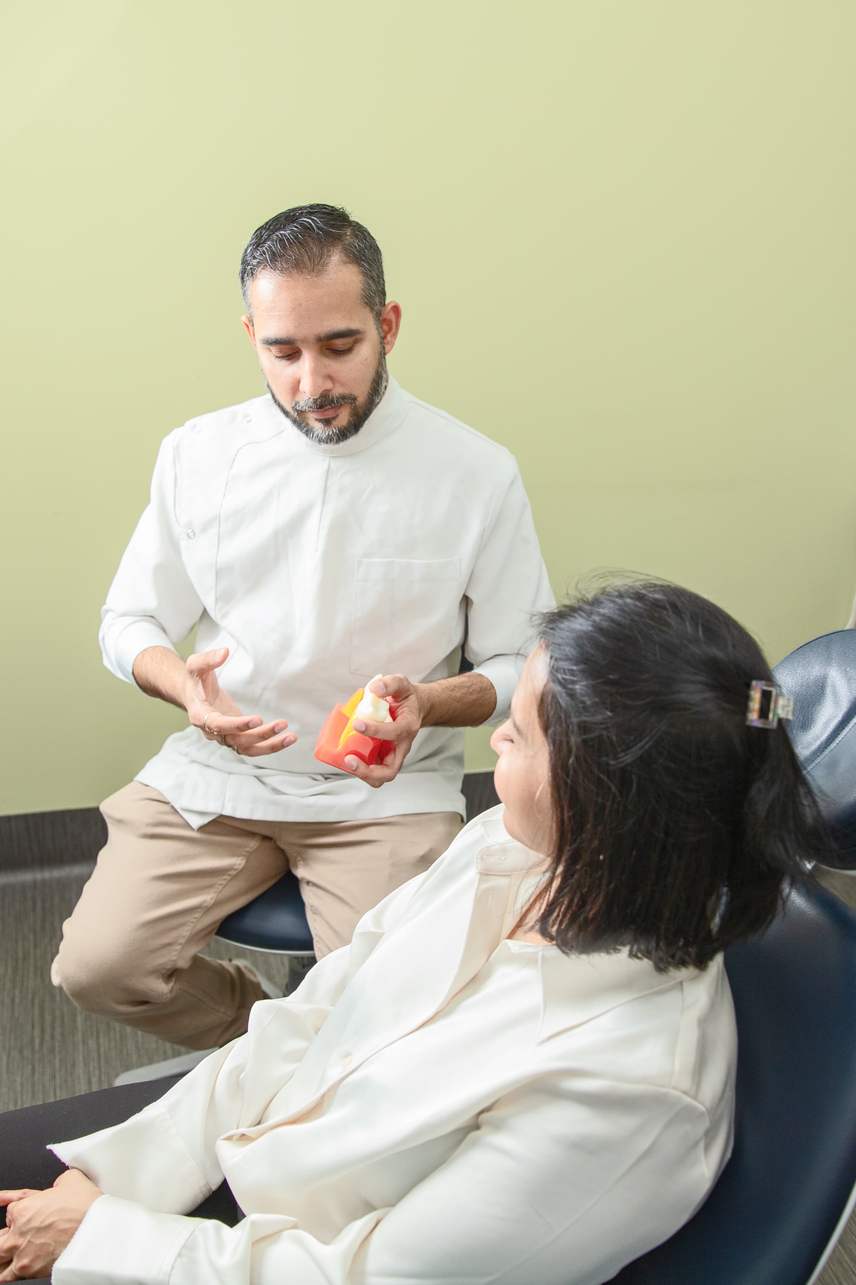 A dentist discussing a dental model with a patient at Dapto Dentists.